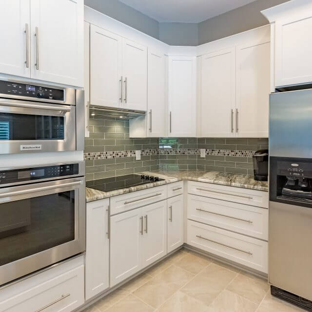 Services include installation of White Shaker cabinets with crown molding, glass tile backsplash and stainless steel appliances and hardware.