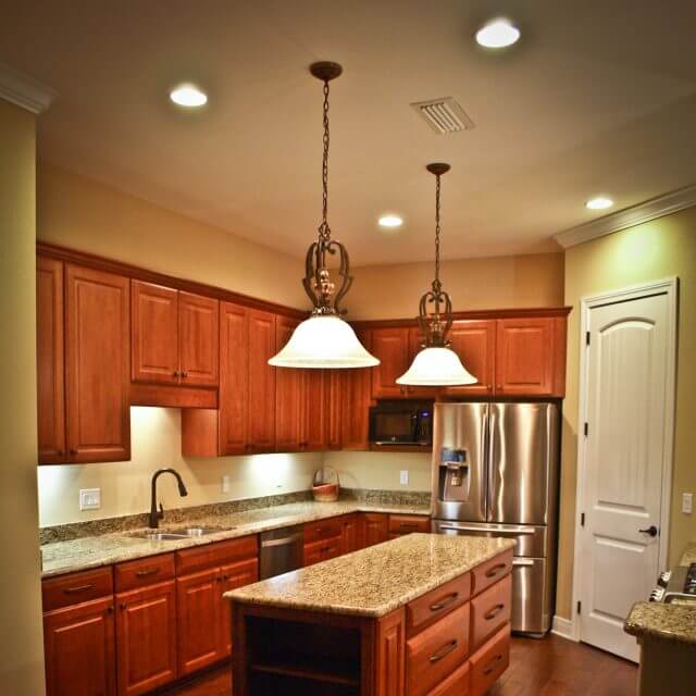Kitchen island with traditional pendant lighting and custom wood cabinets