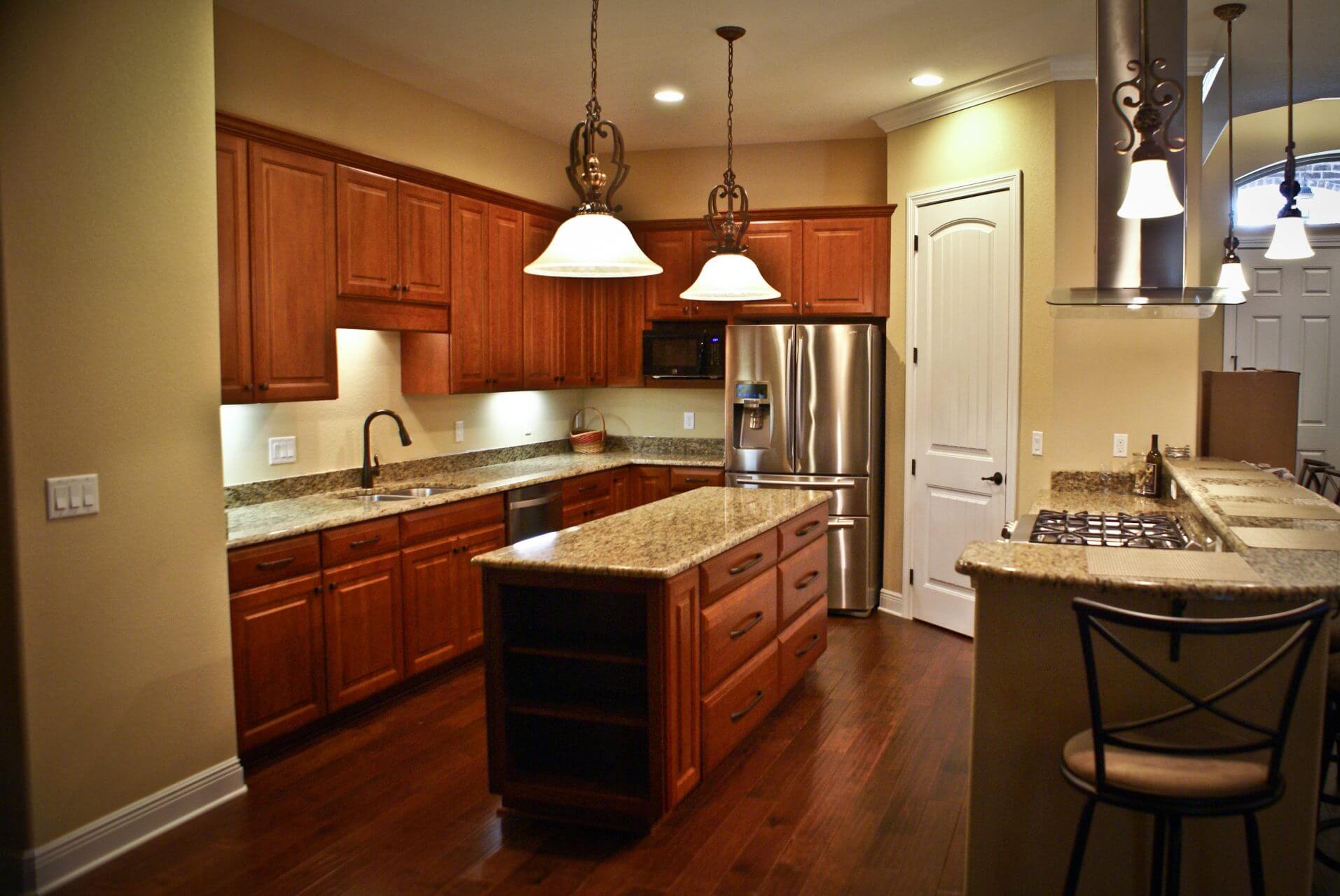 Transitional kitchen with rich wood cabinets, granite countertops and wood floors