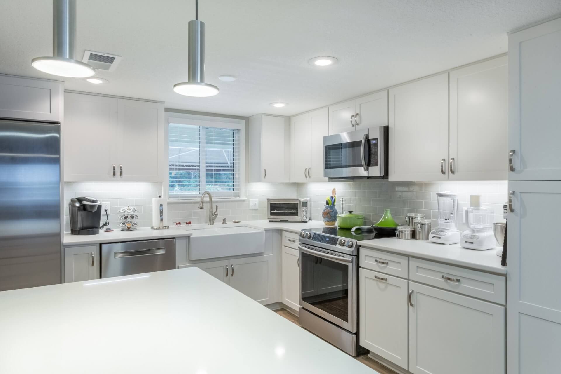 Modern light fixtures accent this Pensacola Beach home kitchen remodel